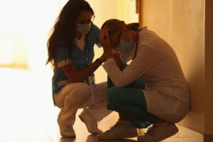A nurse comforts a coworker in the hallway. This could represent the Covid trauma that online depression therapy in New Jersey can offer support with. Learn more about therapy in Swedesboro, NJ by contacting a therapist in South Jersey today! 08085