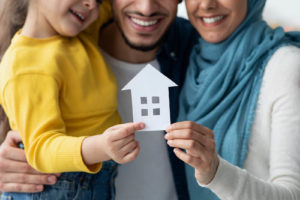 A close up of a family holding a paper house together as they smile. This could represent the support parent counseling in South Jersey can offer. Learn more about parent counseling in Washington, NJ, or contact a parent counselor to learn how counseling for family issues in Swedesboro, NJ can support you! 08085