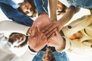 A group of teens join hands in group support as they smile down at the camera. Learn more about teen counseling in South Jersey & get in contact with a therapist in Washington, NJ or Swedesboro, NJ today! 08085