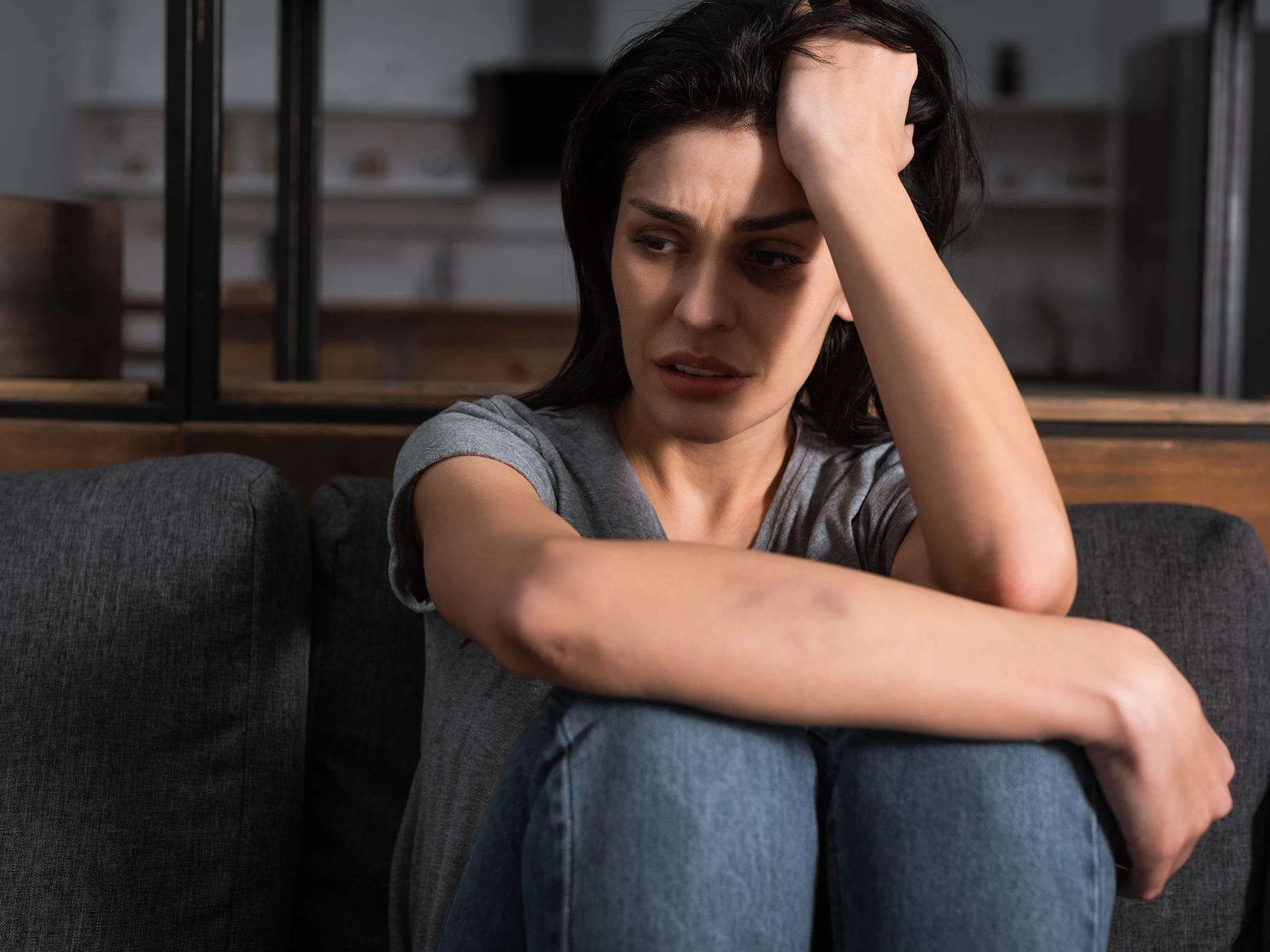 a woman sitting on a couch holding her head