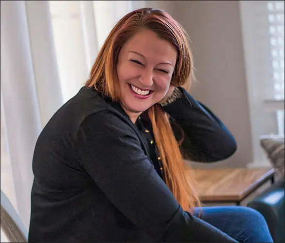 a smiling woman sitting at a table with a laptop