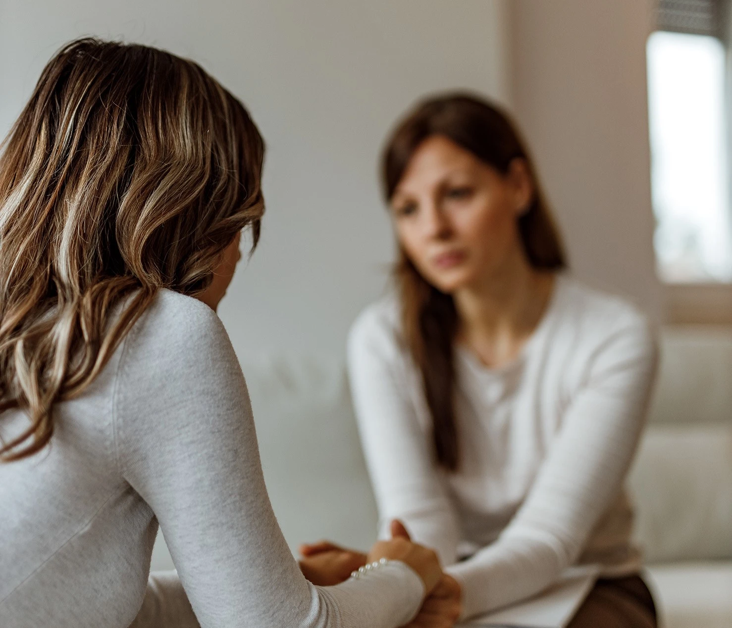 two women sitting on a couch talking to each other