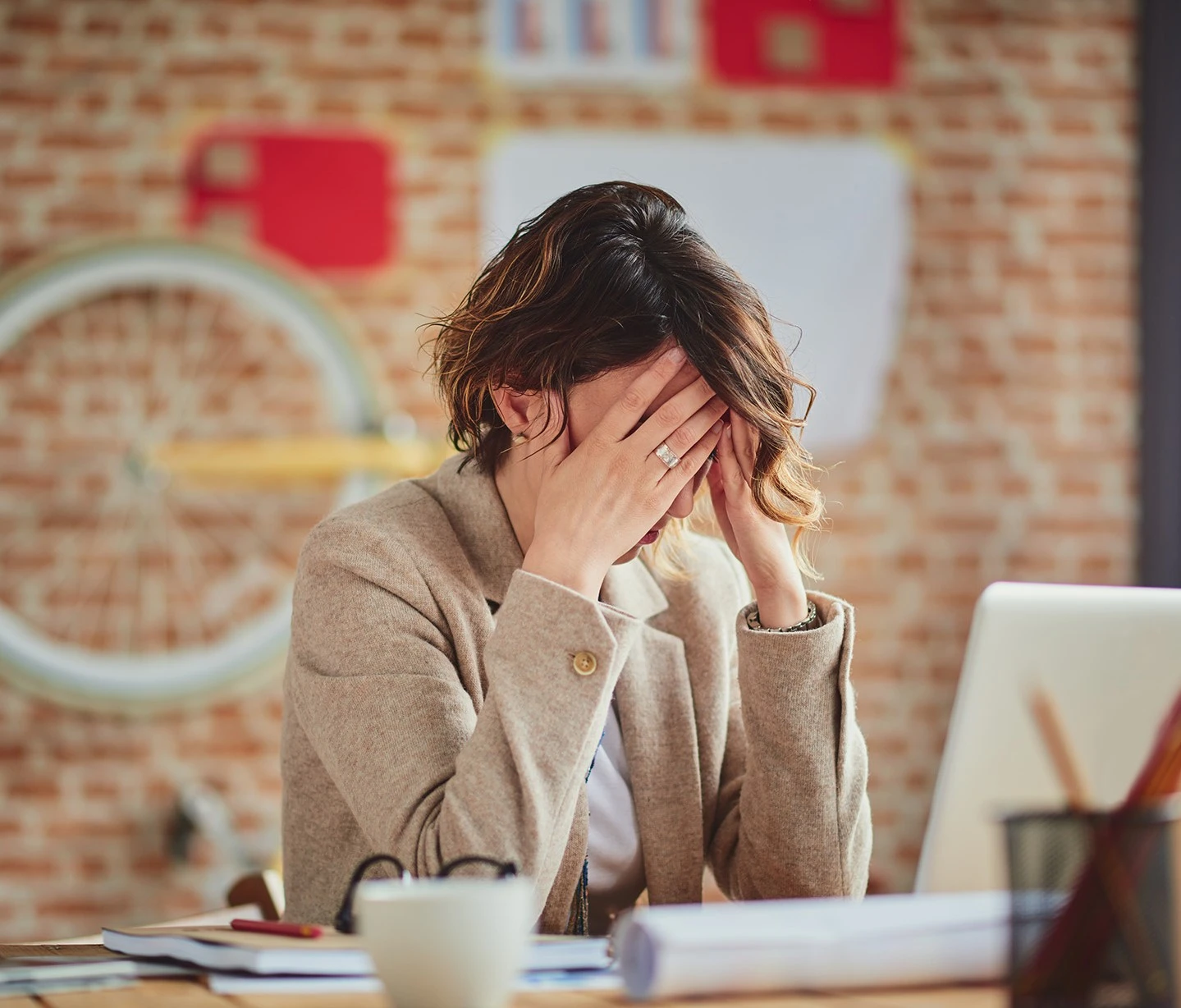 a woman sitting at a desk with her hands on her face