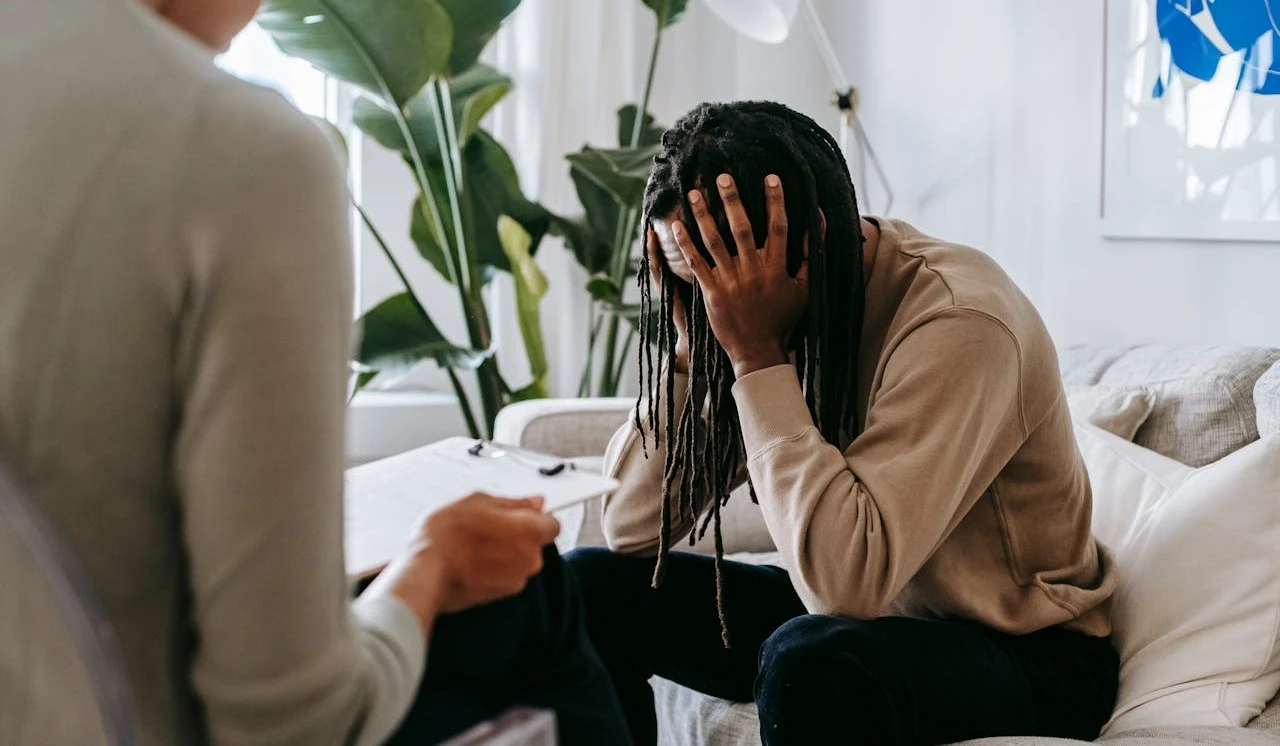 a man sitting on a couch with her head in her hands