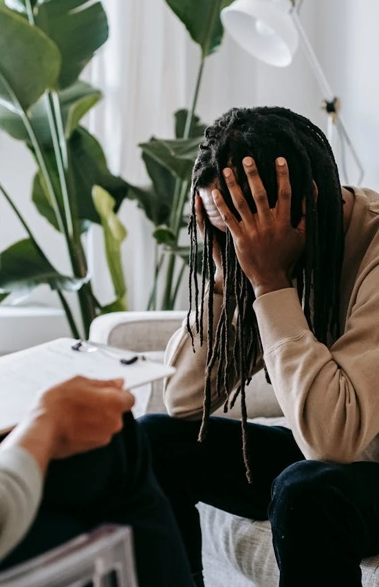 a man with dreadlocks sitting on a couch next to a woman