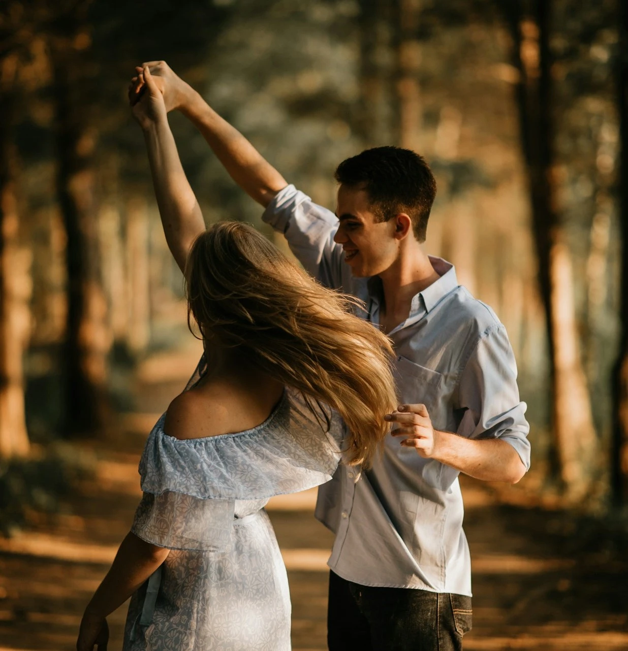 a man and a woman dancing in the woods