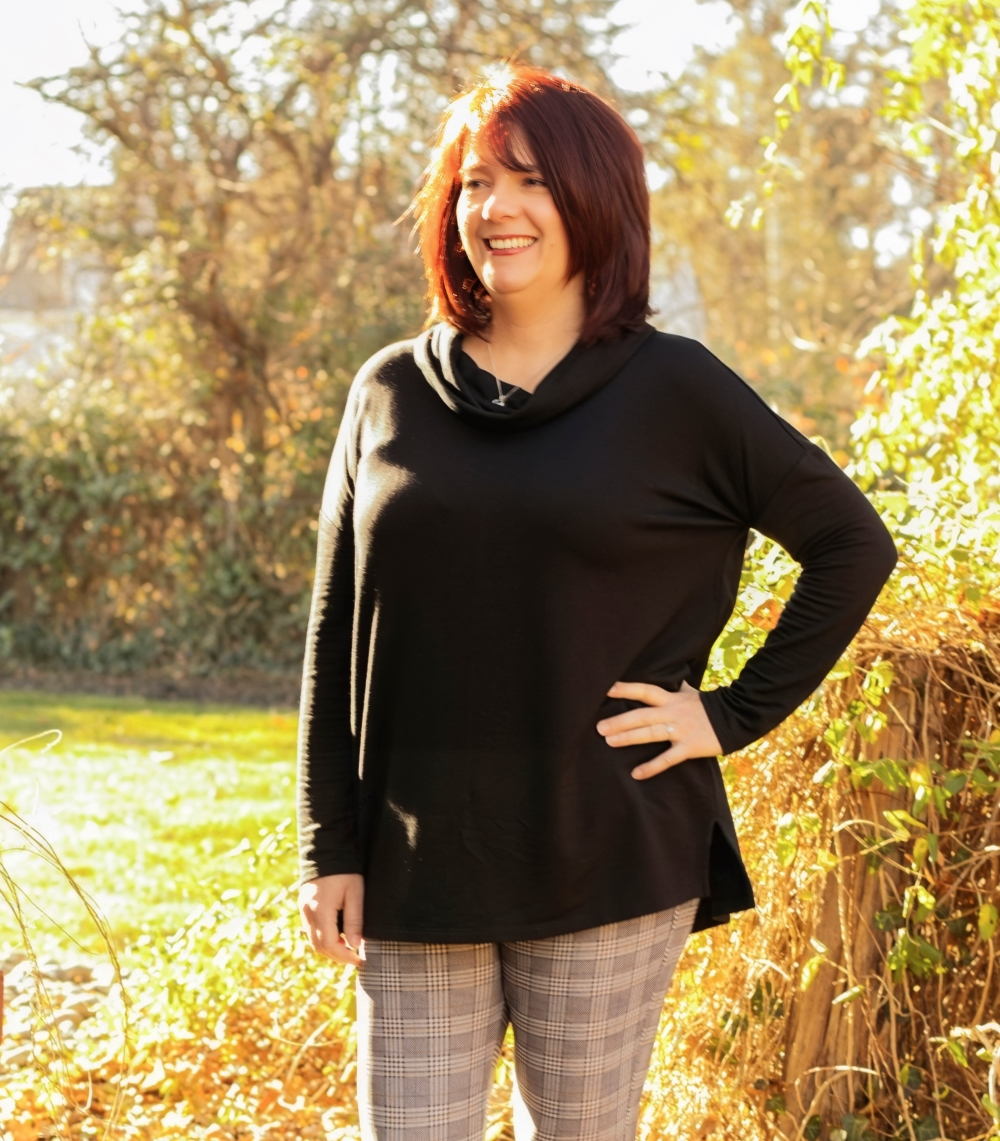 a woman standing in front of a bush with her hands on her hips