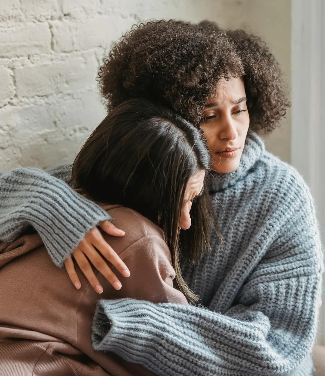 two women hugging each other on a couch