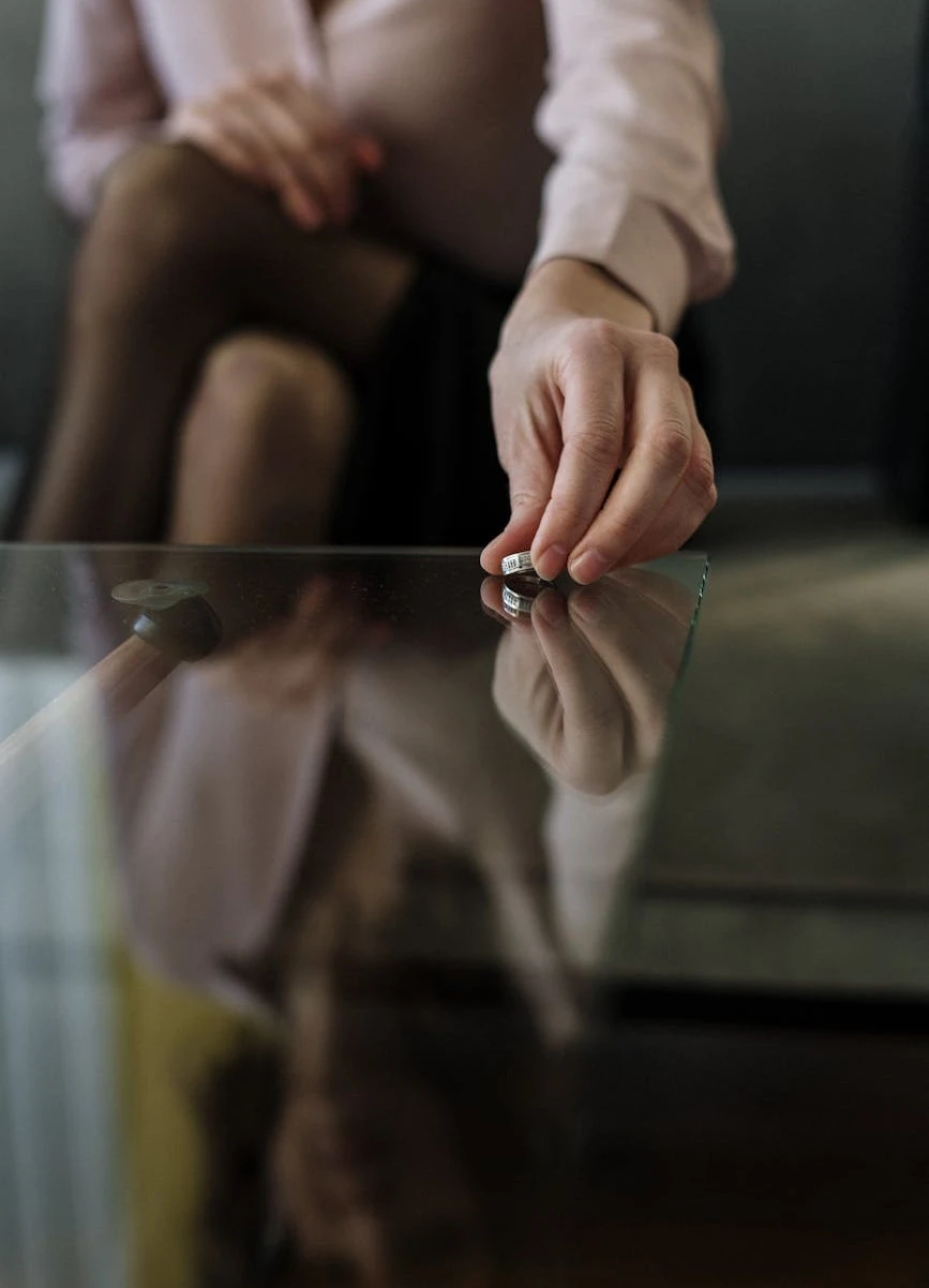 a woman sitting on a couch holding onto a glass table