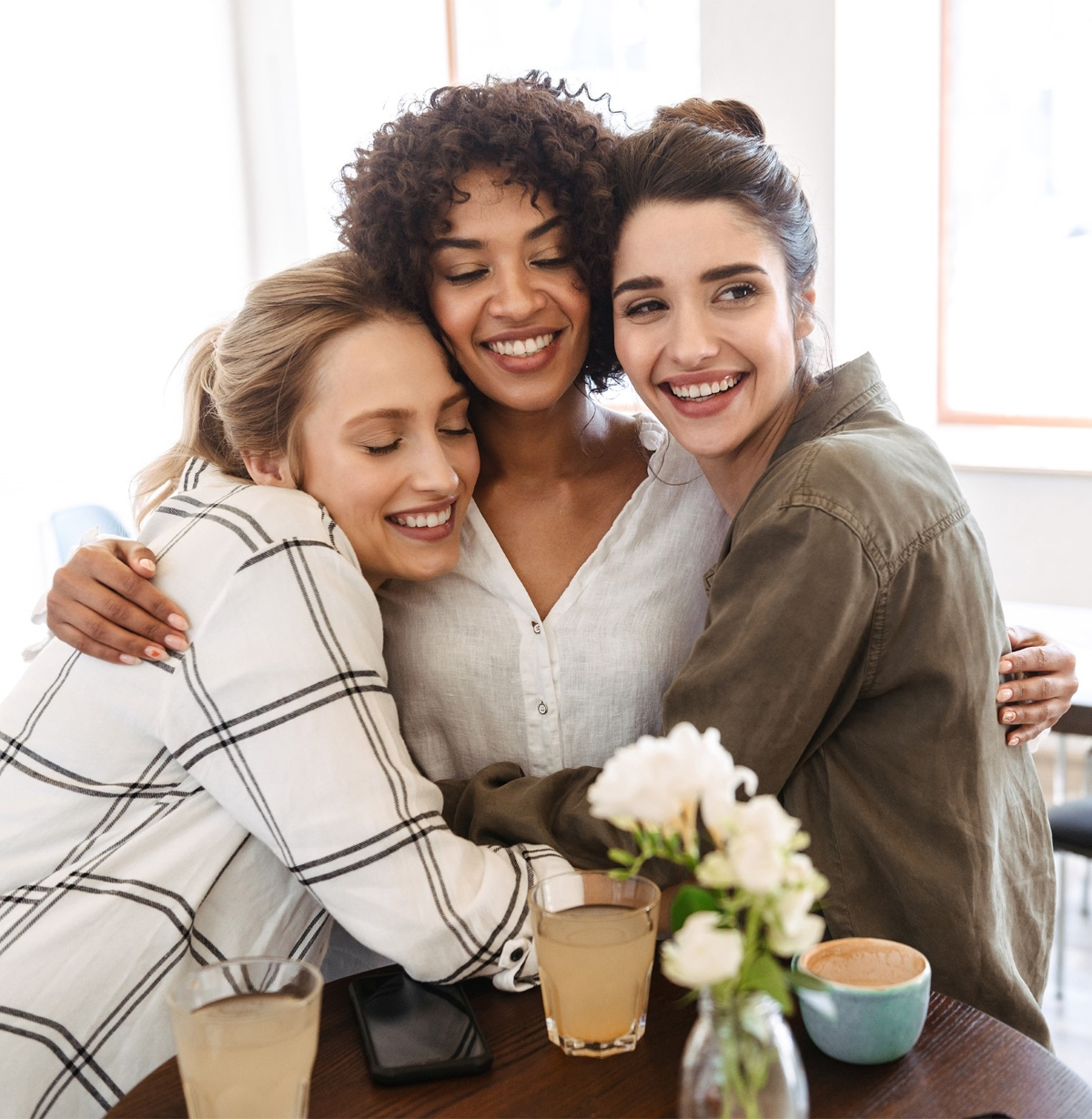 three women hugging each other at a table