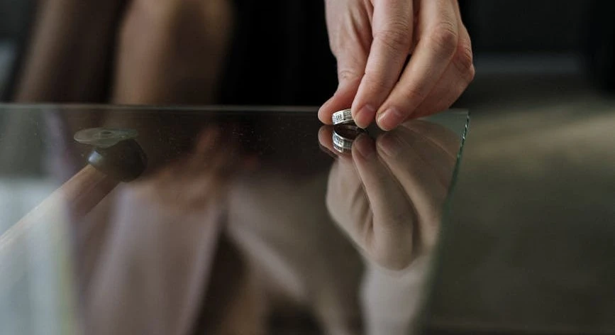 a person holding onto a glass table with a ring on it