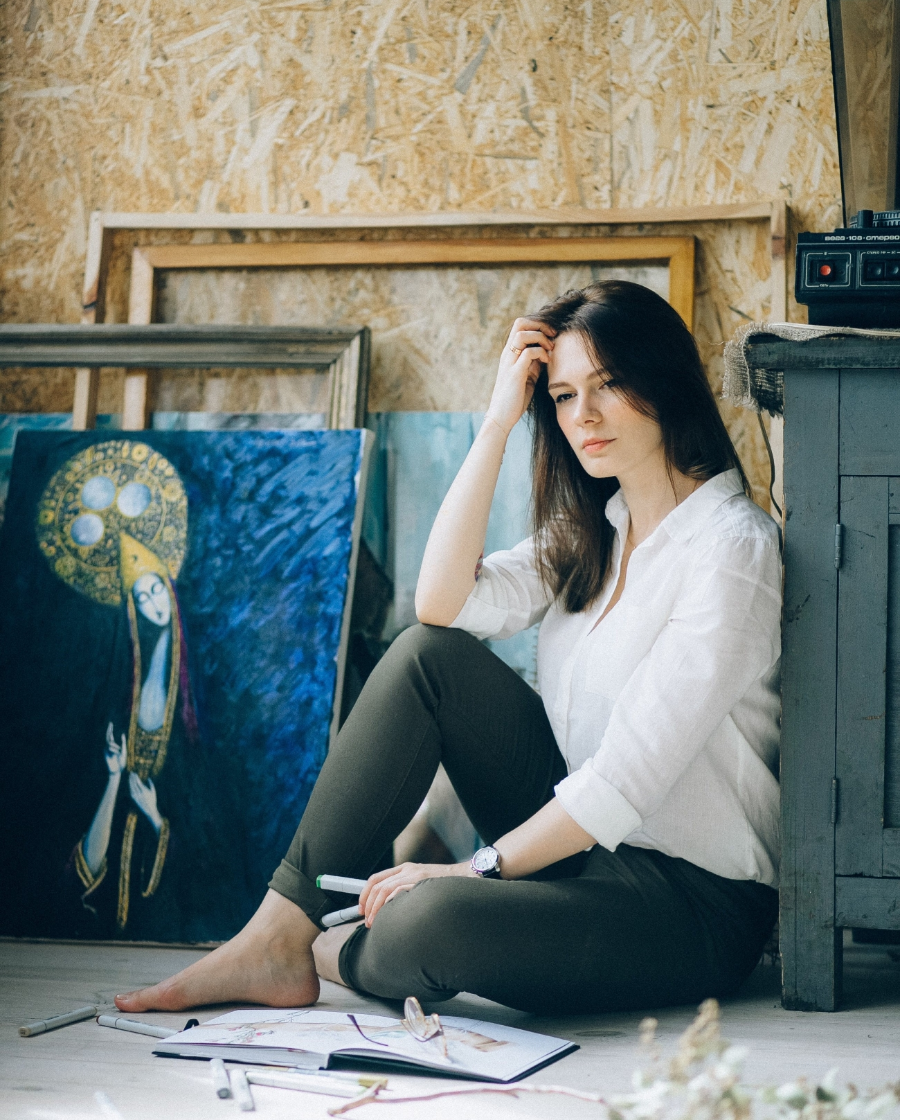 a woman sitting on the floor in front of a painting