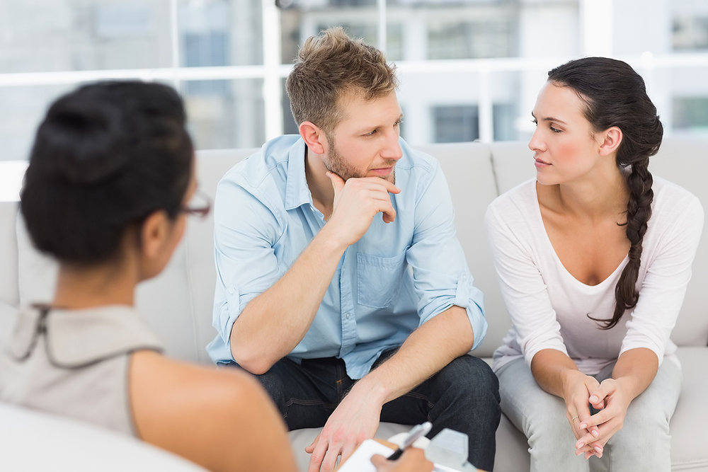 a man and woman sitting on a couch talking to each other