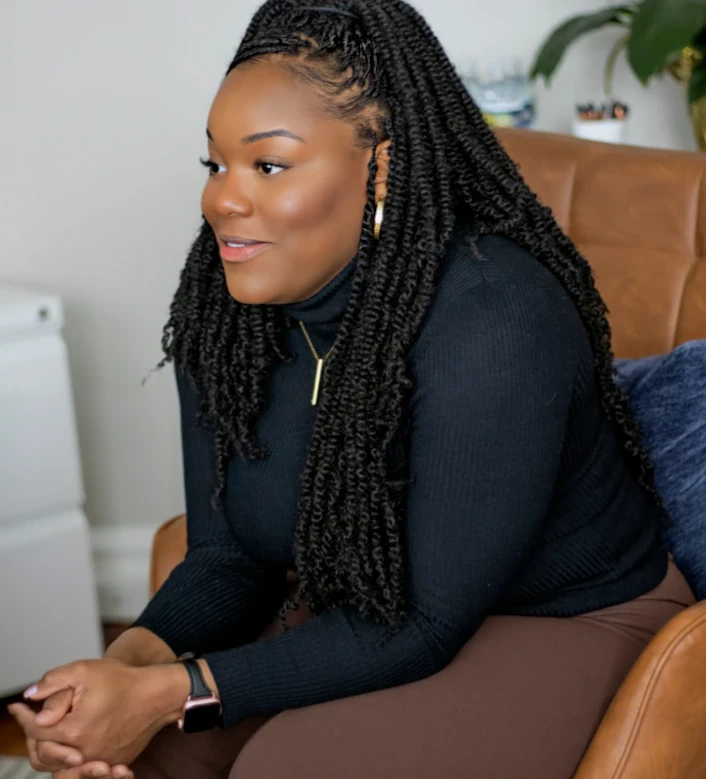 a woman named Asia McNeil sitting in a chair with a black shirt on