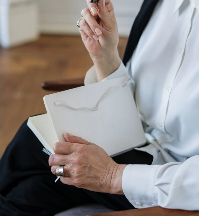 a man in a white shirt is holding a pen and a book