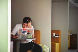 a person holding a cup of coffee while using a laptop