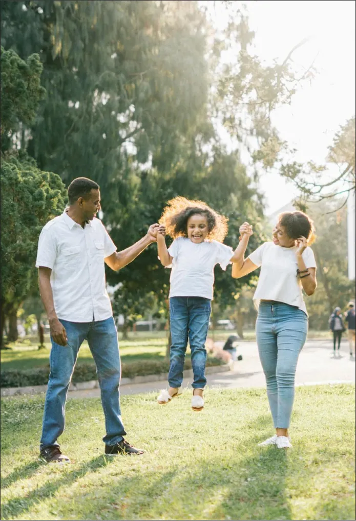 a family of three enjoy playing in a park