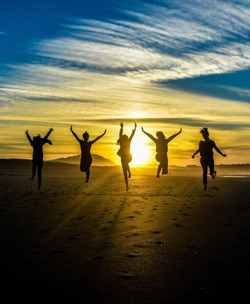 a group of people jumping in the air on a beach