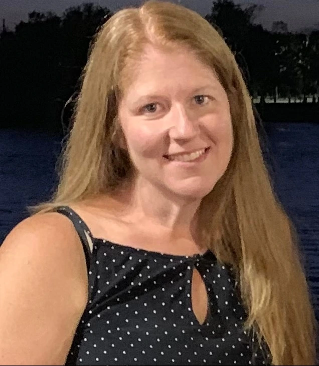 a woman named Jennifer Hess with long blonde hair standing in front of a body of water