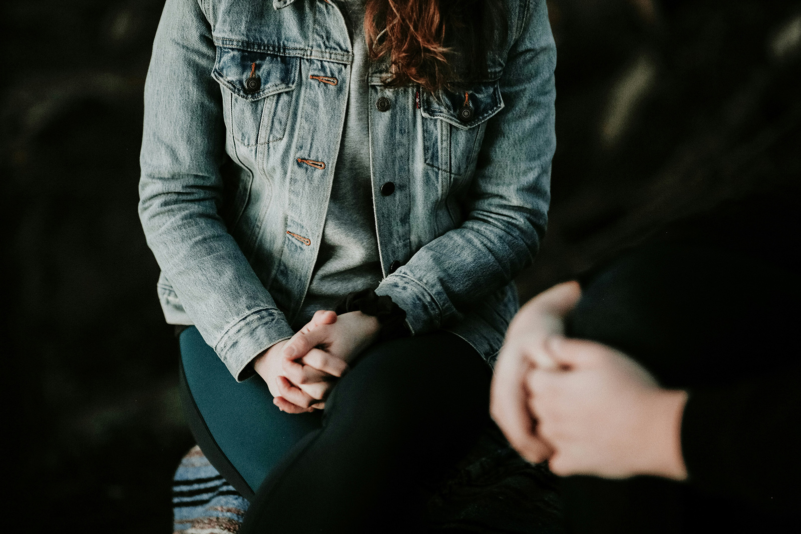 a woman in a jean jacket sitting on a bench