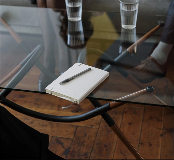 a glass coffee table with a notepad and pen