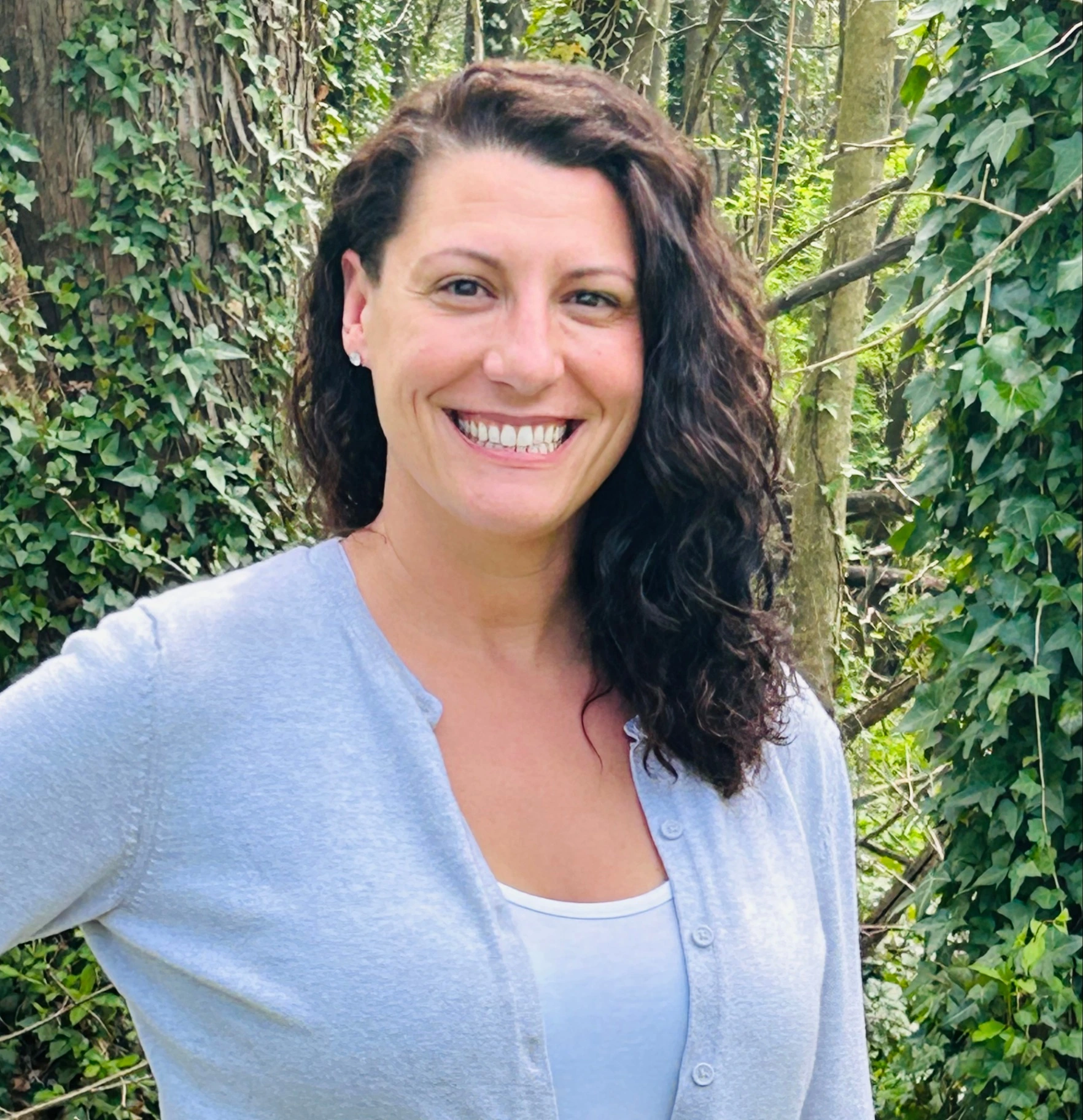 a woman Shannon Galina standing in front of a lush green forest