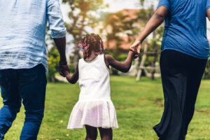 A family join hands as they walk across an grassy field. Contact a parent counselor in Swedesboro, NJ to learn more about parent counseling in Mullica Hill, NJ. Counseling for family issues can offer the support you family deserves! 08085