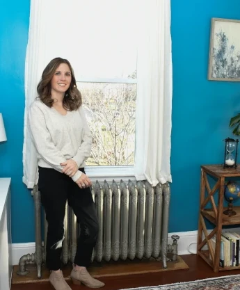 a woman sitting on a radiator next to a window