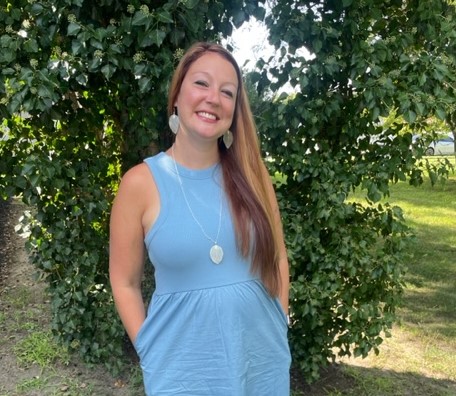 a woman named Jillian Young in a blue dress standing in front of a tree