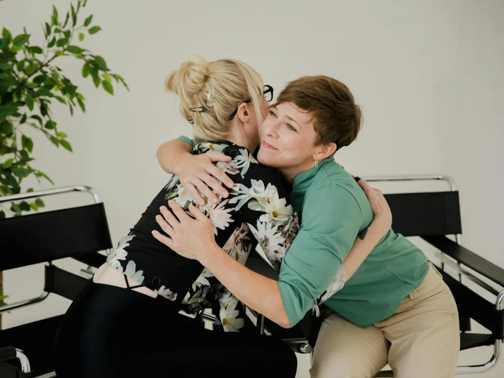 two women hugging each other while sitting on a bench