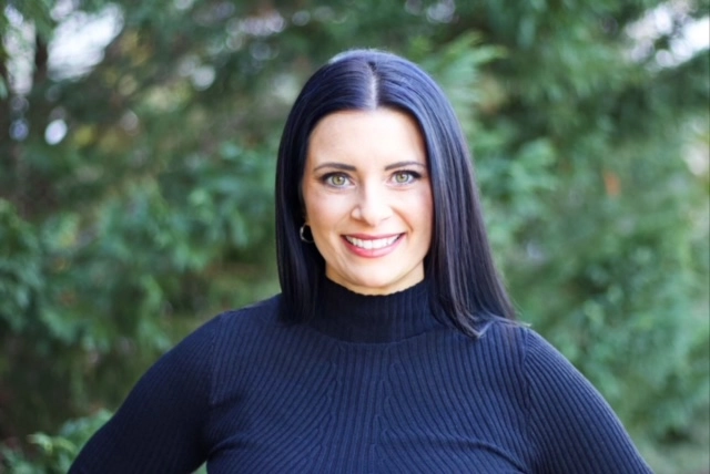 a woman named Michelle Leyman in a blue sweater posing for a picture