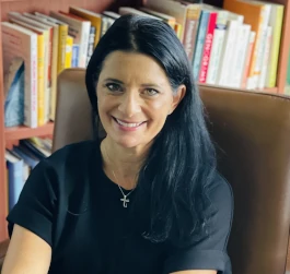 a woman smiling with a bookshelf on the back