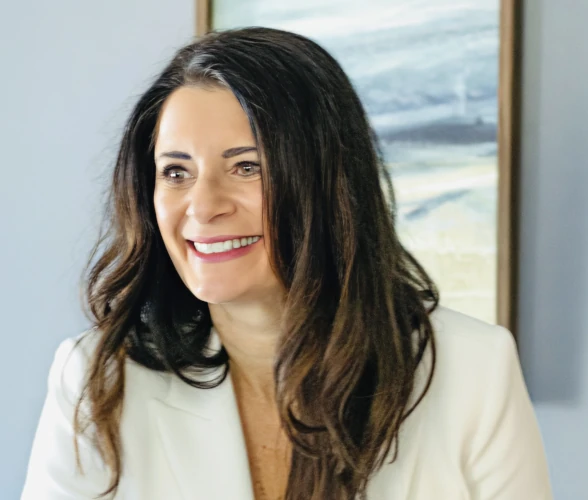 a woman smiling while wearing a white jacket